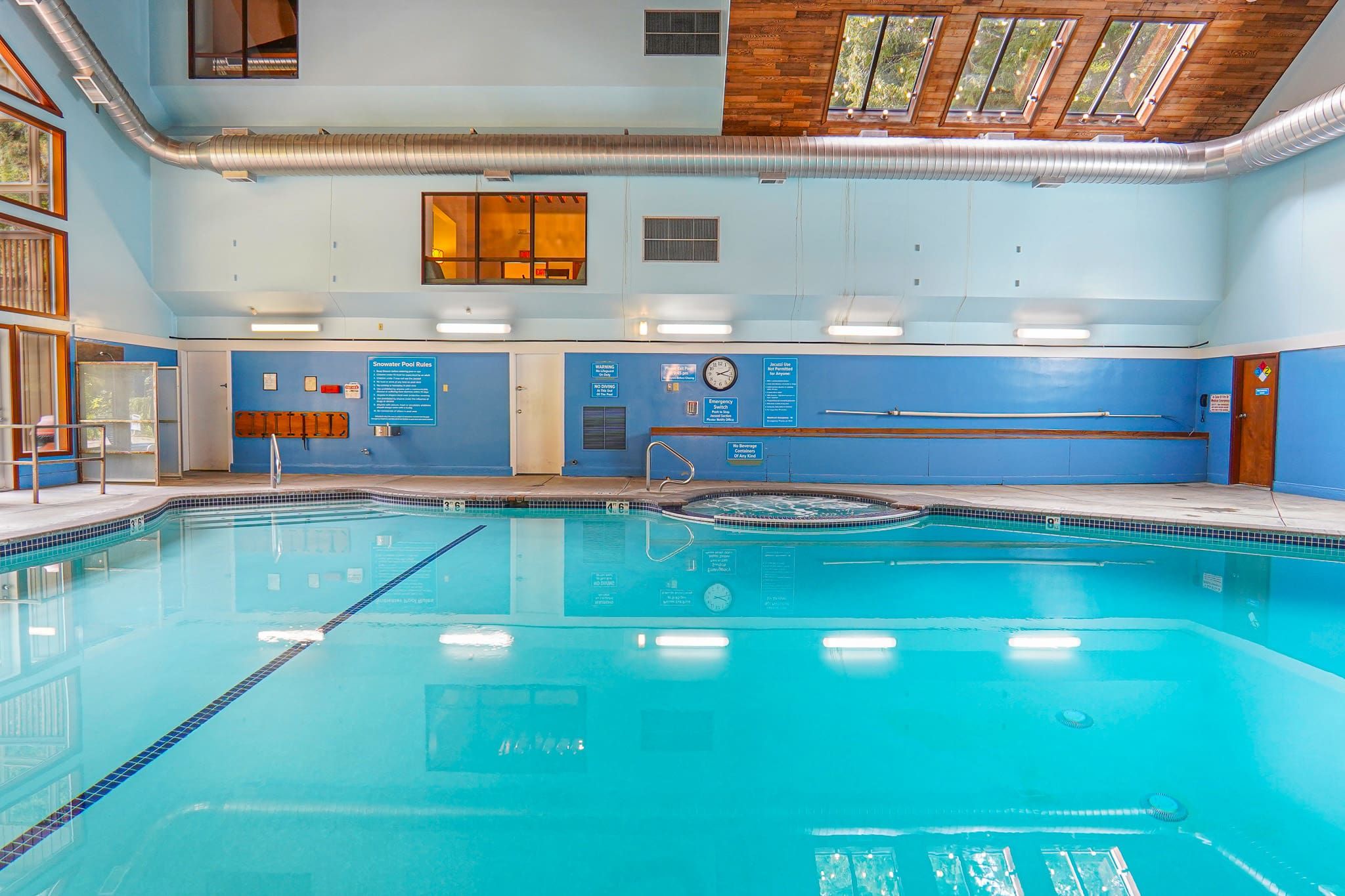 An indoor swimming pool with clear water, marked lanes, and safety signs.