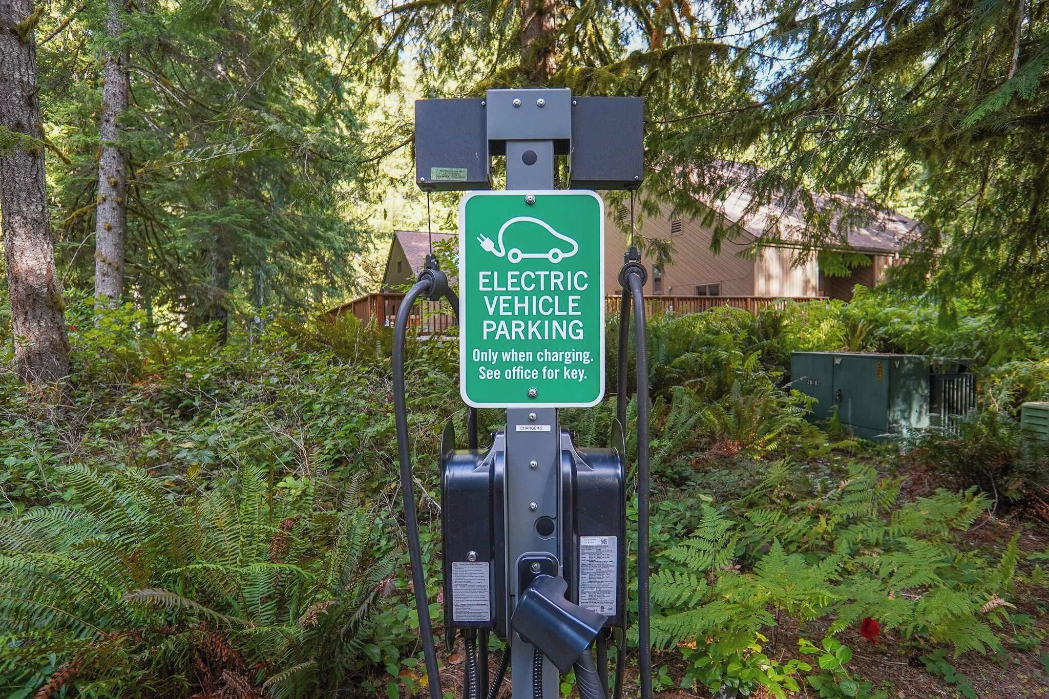 An electric vehicle charging station with a sign indicating it is for electric vehicle parking only when charging.