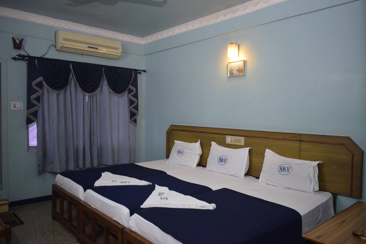 A double bed with two pillows, a wooden headboard, and a wall-mounted air conditioner.