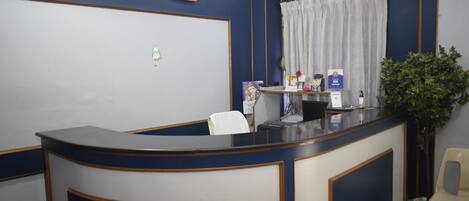 Una recepción con decoración azul y blanca, un reloj en la pared y una planta a la derecha.