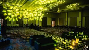 A spacious hall with rows of chairs and a stage, featuring a patterned floor and green seating areas. - Grand Sarovar Portico (Latur)