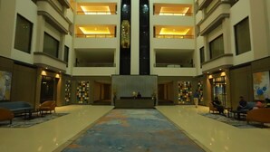 A spacious lobby with a central reception desk, multiple floors, and seating areas. - Grand Sarovar Portico (Latur)