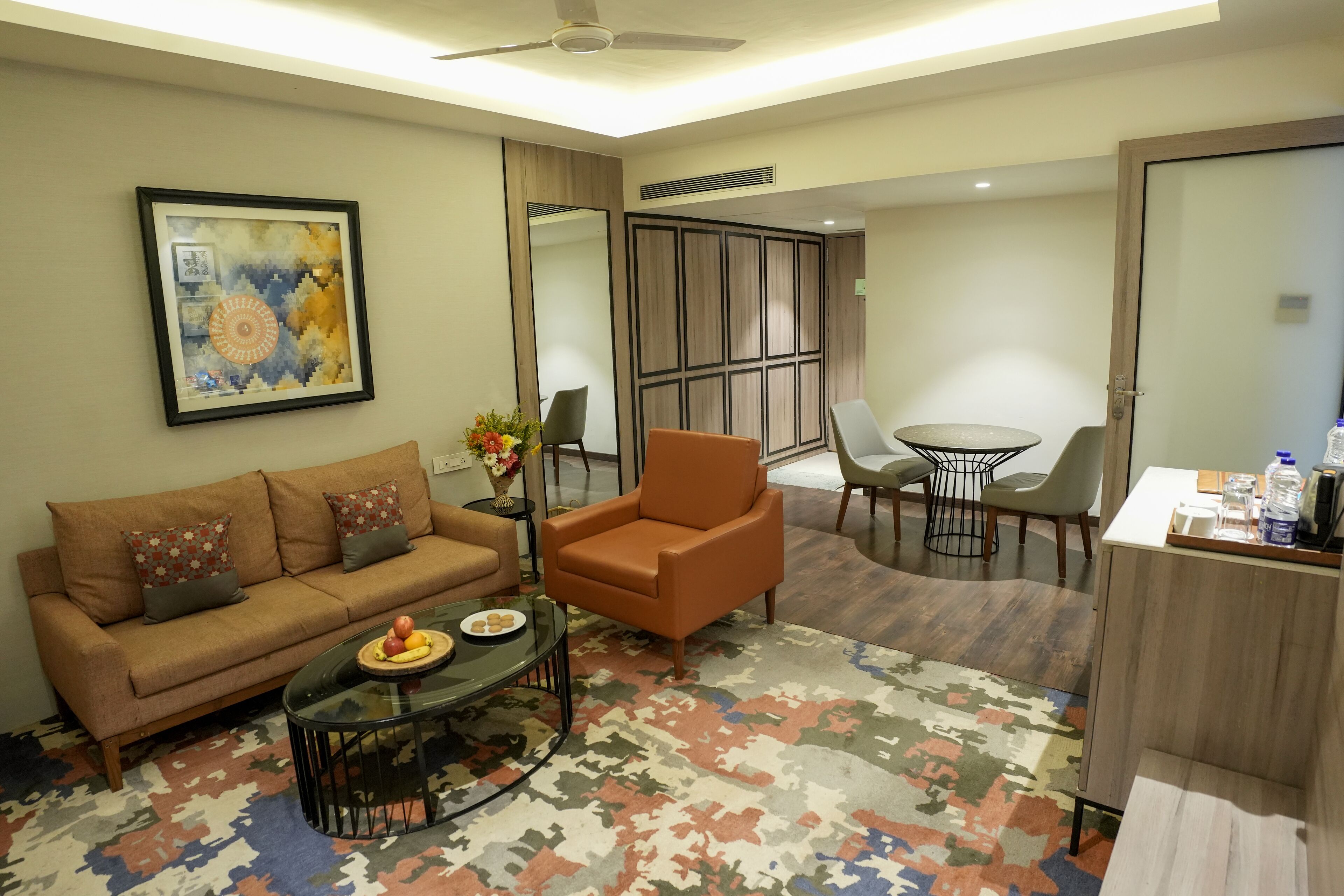 A modern living room with a sofa, armchair, coffee table, and a dining area with chairs and a table.