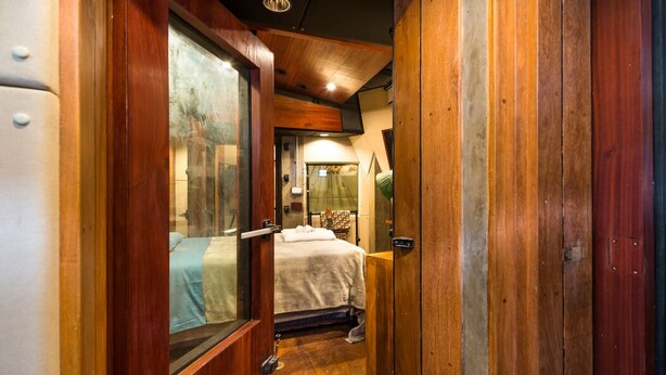 A narrow hallway leading to a bedroom with a bed, a wooden door, and a small window. - VILA MADALENA: BEST LOCATION, ARTISTIC APARTMENT (São Paulo)