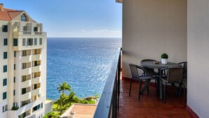 A balcony with a table and chairs overlooking the ocean.