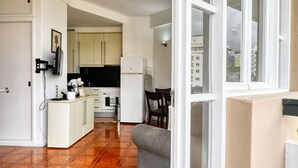 A compact kitchen with white cabinets, a refrigerator, and a dining area with a table and chairs.