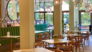L’intérieur d’un restaurant avec des banquettes vertes, des tables en bois et des luminaires suspendus.