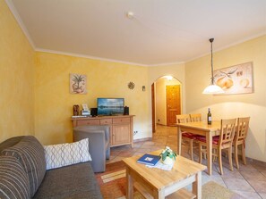 A cozy living room with a sofa, a small table, a TV, and a dining area with chairs and a table. - Residenz Laguna Whg L-19 .. - L-19 (Kühlungsborn)