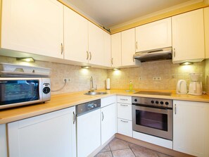 A modern kitchen with white cabinets, stainless steel appliances, and a tiled backsplash. - Residenz Laguna Whg L-19 .. - L-19 (Kühlungsborn)