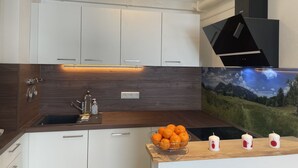 Une cuisine moderne avec des meubles blancs, un plan de travail en bois, un évier et une cuisinière.