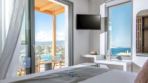 Ein Hotelzimmer mit Bett, Fernseher, Schreibtisch und Blick auf Meer und Berge.