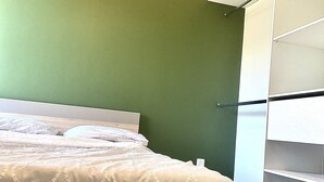 A bedroom with a bed, green walls, and a white wardrobe. - 77m2 T4 apartment (La Seyne-sur-Mer)