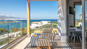 Un balcone con sedie in vimini, un tavolino con bevande e vista sul mare e sulla città.