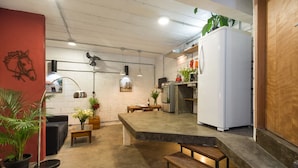 A modern kitchen with a white refrigerator, a dining area with a bench, and a red accent wall with a horse sculpture. - VILA MADALENA Perfect Location: Artistic Apartment (SP)