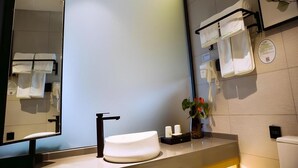 Une salle de bain moderne avec un grand miroir, un lavabo blanc et un porte-serviettes.