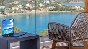 Un portátil sobre una mesa, con vista a un lago y edificios al fondo.