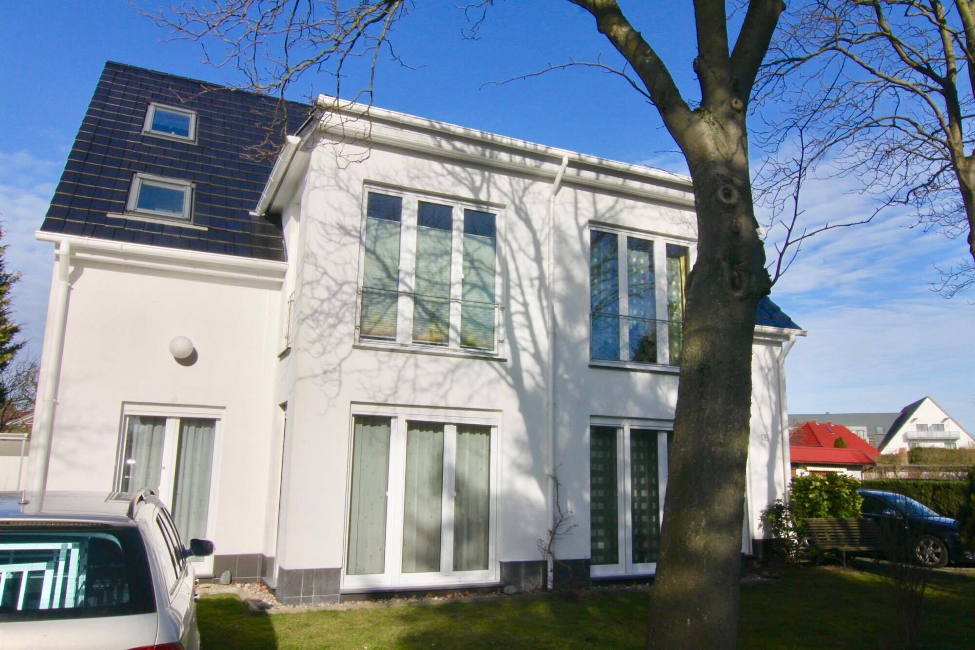 A two-story house with large windows and a tree in front.