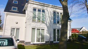 Ein zweistöckiges Haus mit großen Fenstern und einem Baum davor.