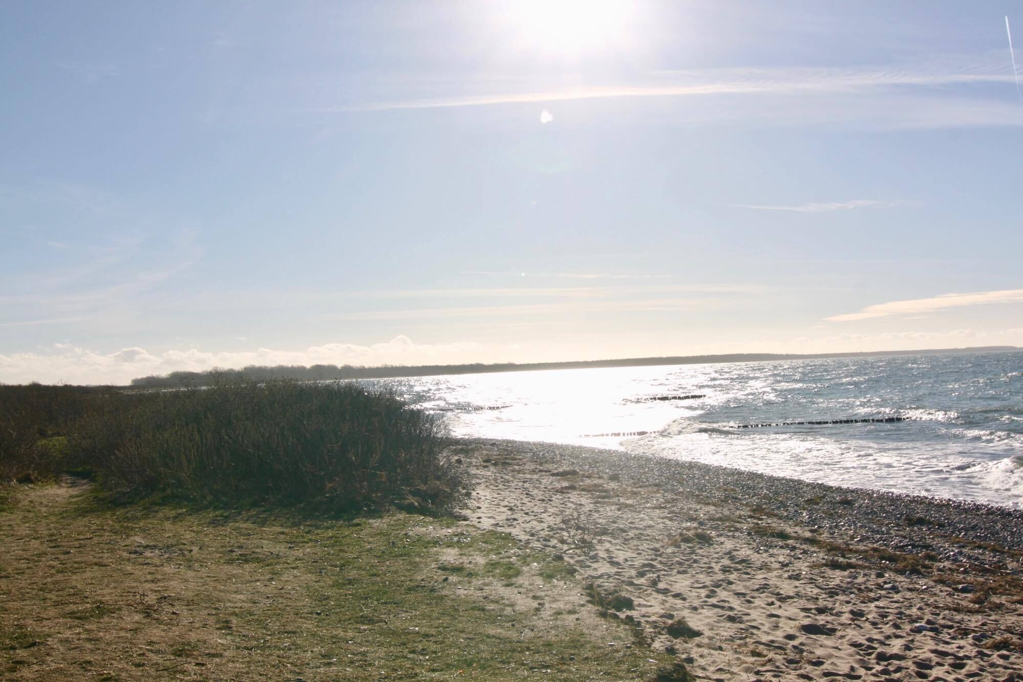 A beach with a clear sky and sunlight reflecting off the water.