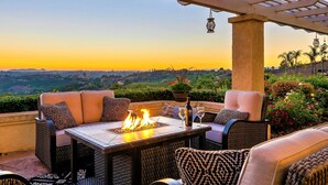 Une terrasse extérieure aménagée avec des meubles en osier, un foyer et une vue sur le paysage.