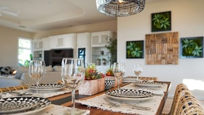 Un coin repas avec une table en bois dressée pour quatre personnes, entourée de chaises en osier.