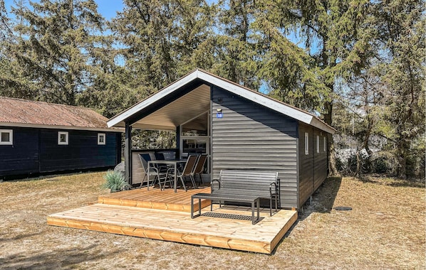 A small cabin with a wooden deck, a covered outdoor seating area, and a number '18' sign.