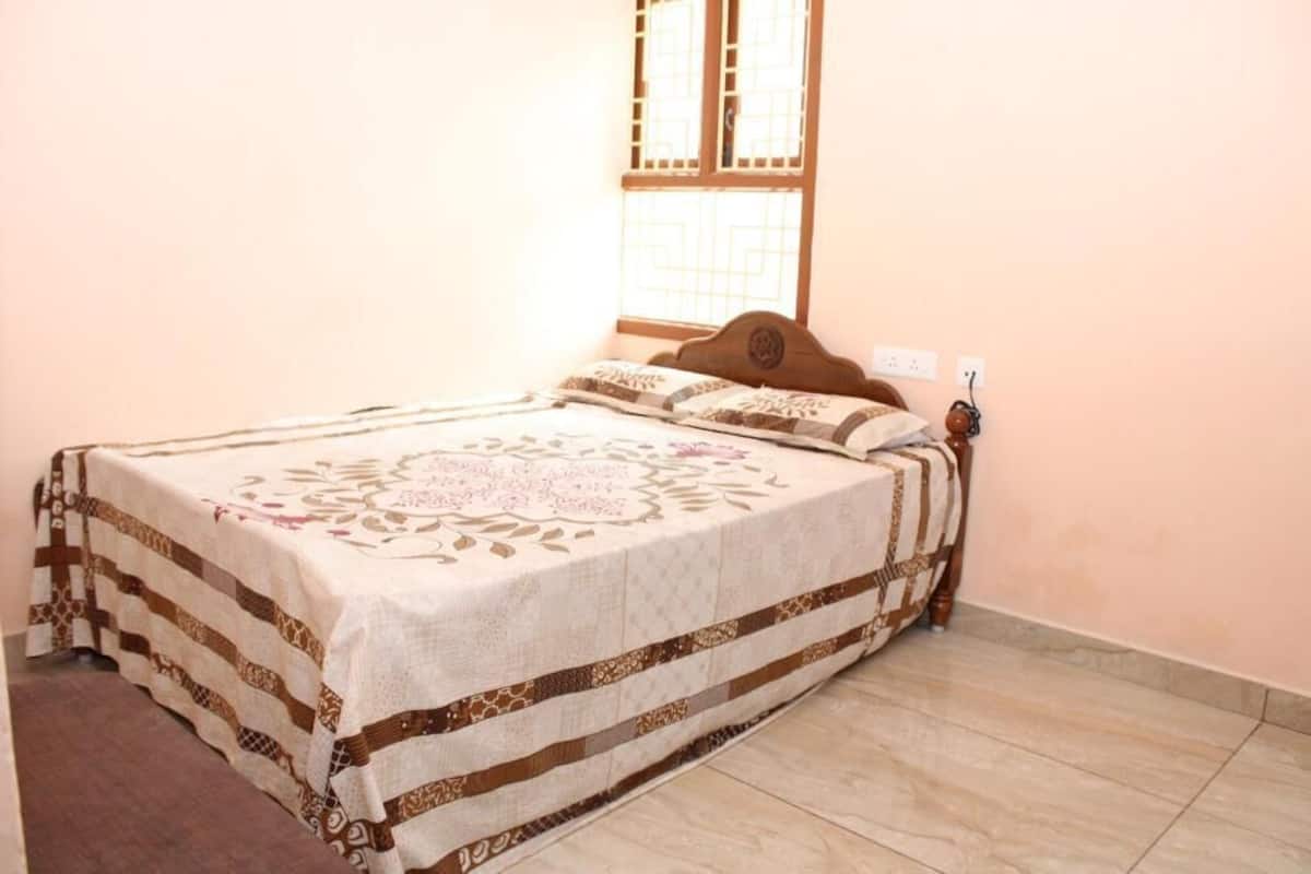 Cama bem arrumada com colcha estampada, cabeceira de madeira e janela com design tradicional.