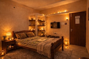 A cozy bedroom with a wooden bed, bedside lamps, a TV, and shelves with books and decorative items.