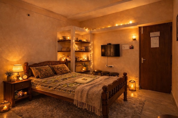 Un dormitorio acogedor con cama de madera, lámparas de noche, televisión y estantes con libros y objetos decorativos.