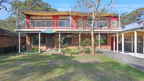 A two-story building with a red facade, a balcony, and a sign that reads "BARRALONG". - Barralong Beach House (Hawks Nest)