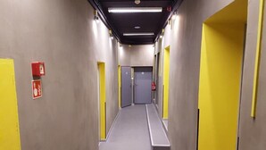 A hallway with yellow doors, a fire alarm, and a fire extinguisher.