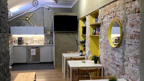 A compact kitchen with modern appliances, a dining area with wooden furniture, and a brick accent wall.