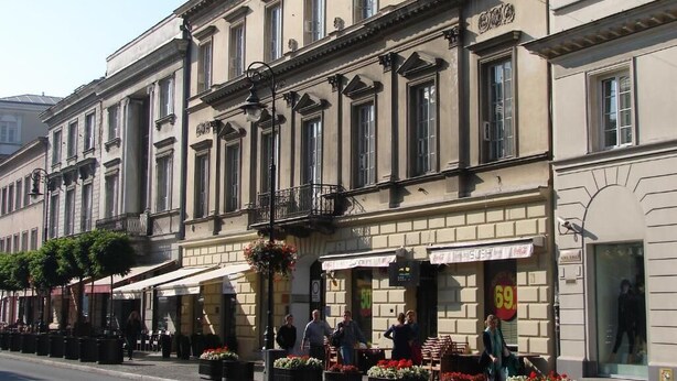 A row of buildings with a row of outdoor seating areas in front.