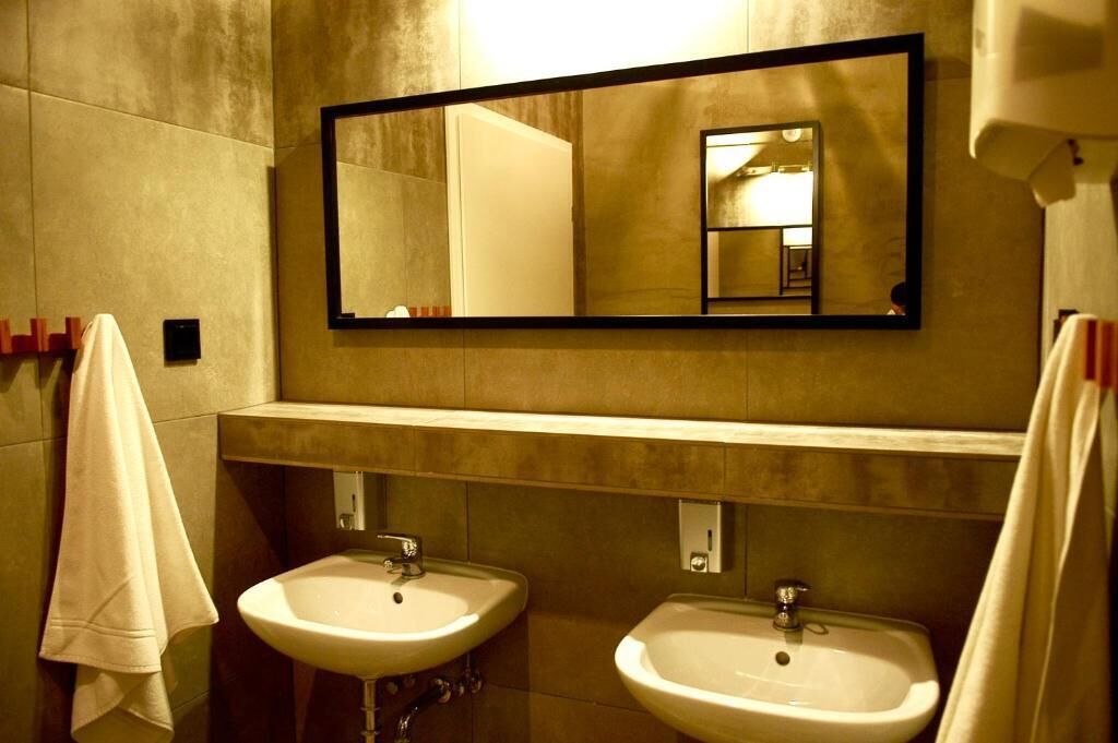 Uma casa de banho com duas pias, um espelho grande e toalhas na parede.