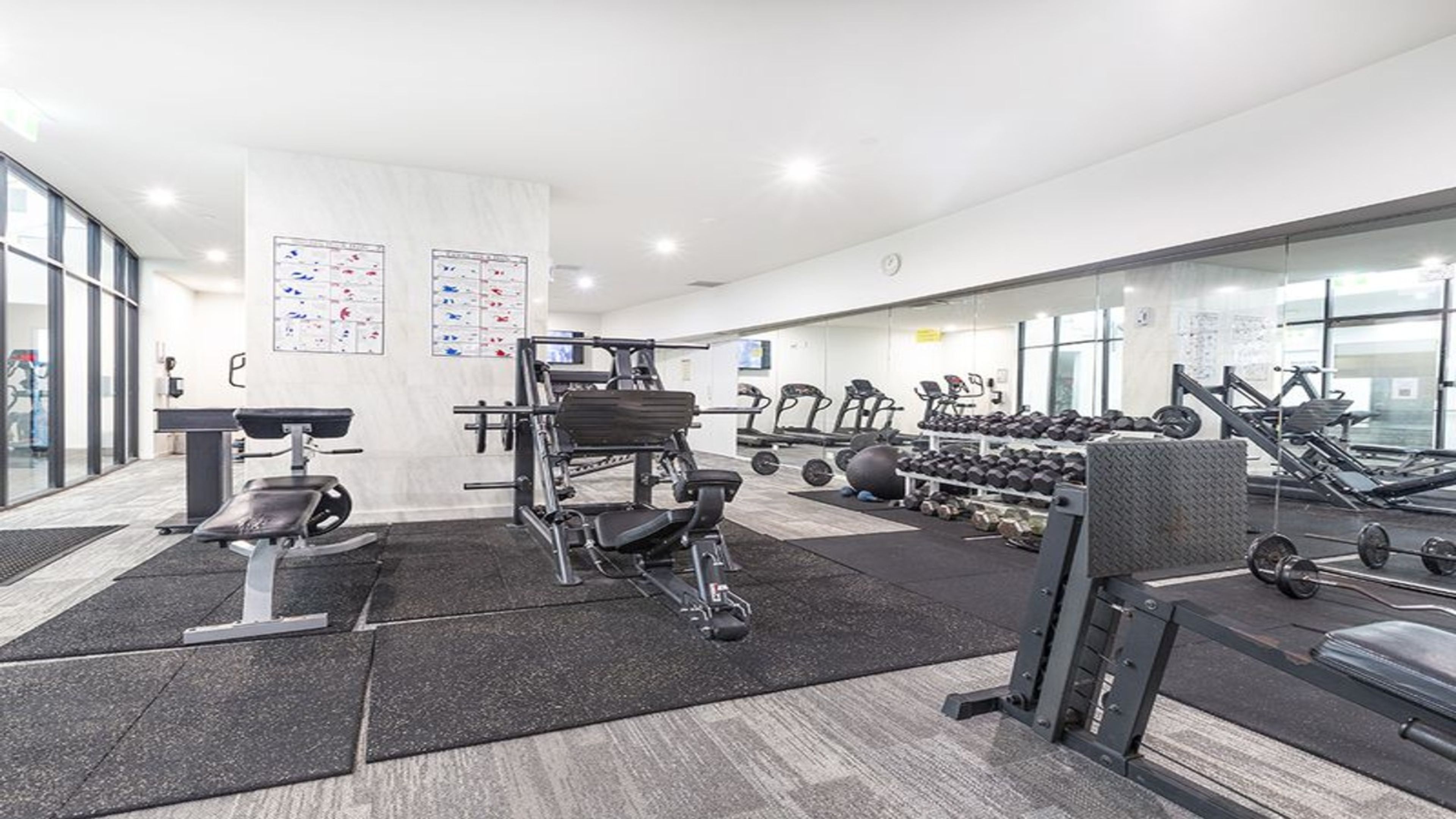 Een fitnessruimte met diverse trainingsapparaten, waaronder loopbanden, gewichten en krachtapparaten.