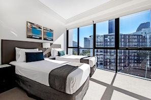 A hotel room with two beds, a large window, and artwork on the wall. - Stunning 2 Bed Apartment in Sierra Grand (Broadbeach)