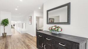 A hallway with a dark wooden console table, a large mirror, and a potted plant. - VISTA ELMS - THE VINTAGE HOLIDAY HOUSES (POKOLBIN)