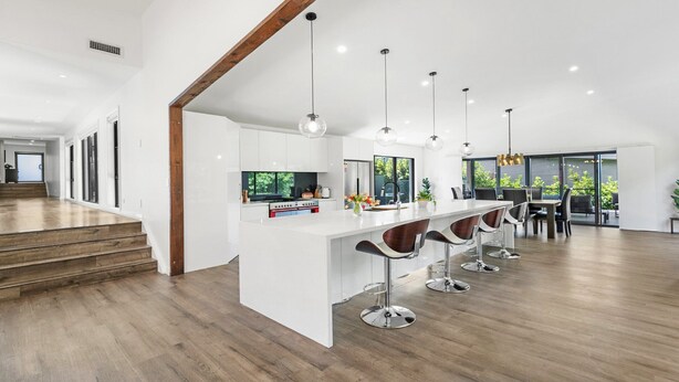 A modern kitchen with a central island, bar stools, and pendant lighting. - VISTA ELMS - THE VINTAGE HOLIDAY HOUSES (POKOLBIN)