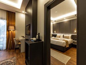 A modern hotel room with a bed, bedside table, lamp, and a view of the city.