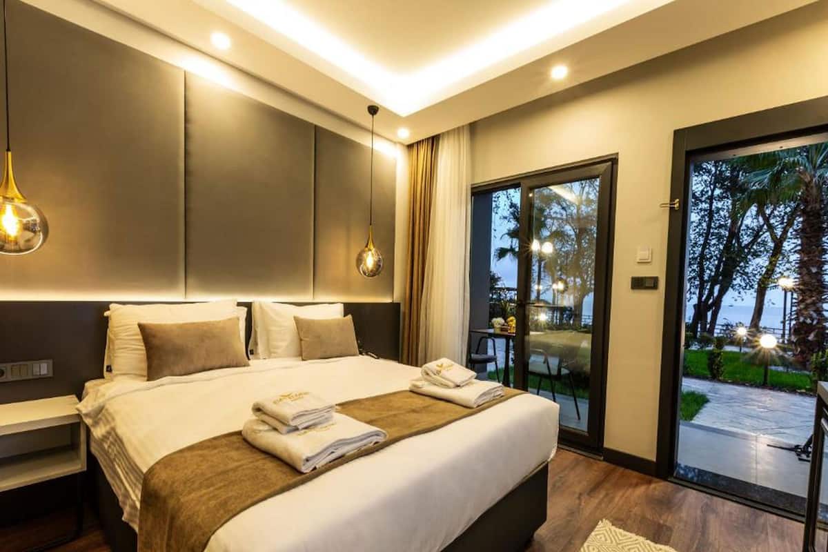 A modern hotel room with a large bed, a desk, and a view of the outdoors.