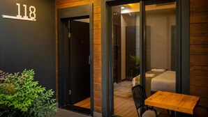 Una entrada de hotel moderna con fachada de madera, puerta de vidrio y un pequeño espacio de estar al aire libre.