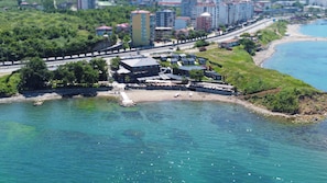 A coastal hotel with multiple buildings, a beach, and a road running parallel to the water. - Santana Resort Hotel (Trabzon)