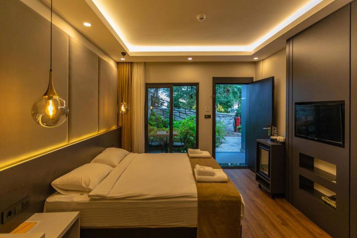 A modern bedroom with a bed, bedside tables, a TV, and a view of the outdoors.