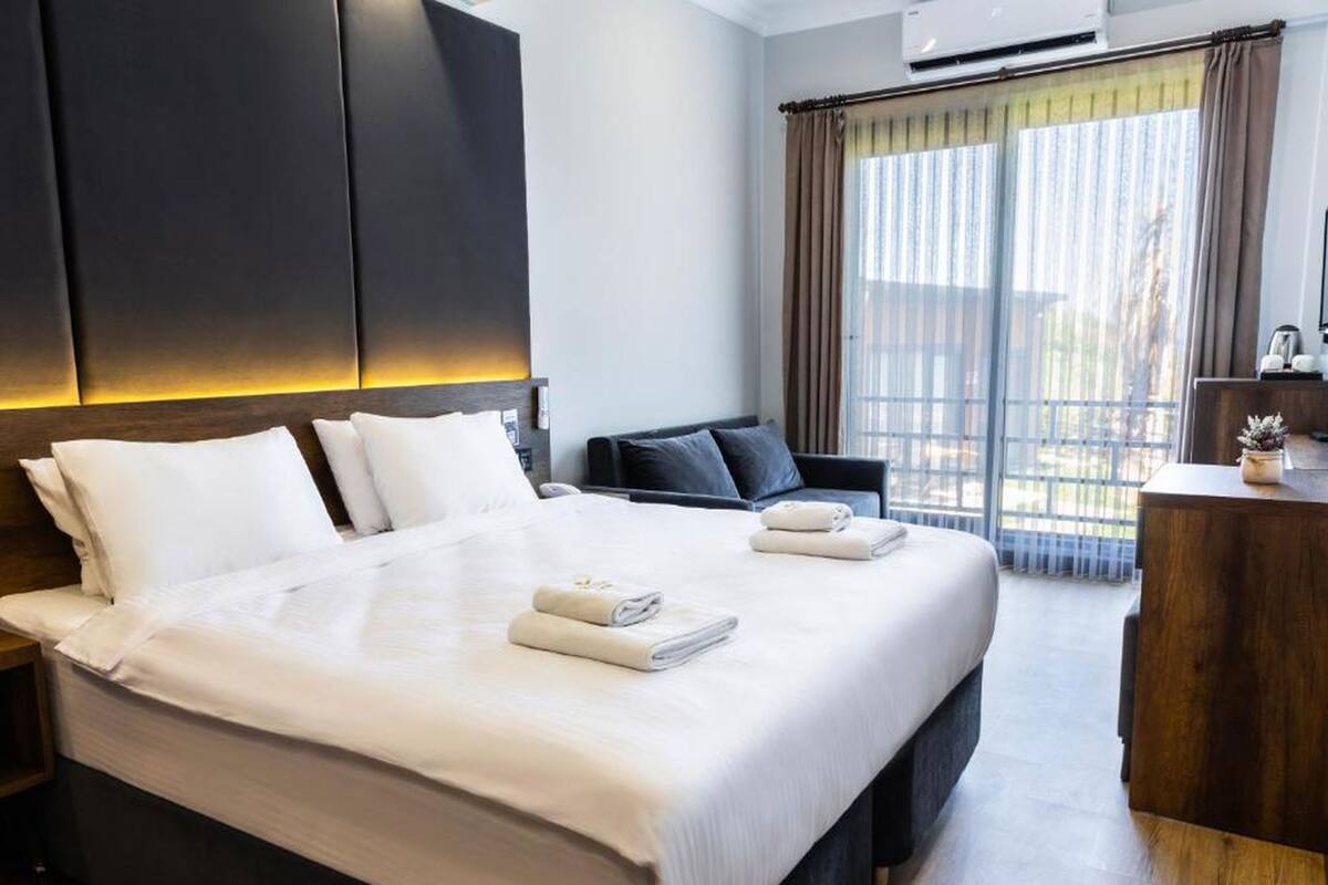 A hotel room with a large bed, a desk, and a view of the outdoors.