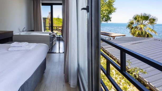 Habitación de hotel con balcón, bañera y vista al mar.