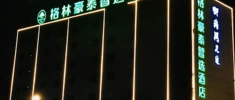 A hotel with a sign indicating it is a 'smart hotel' with a green neon sign.