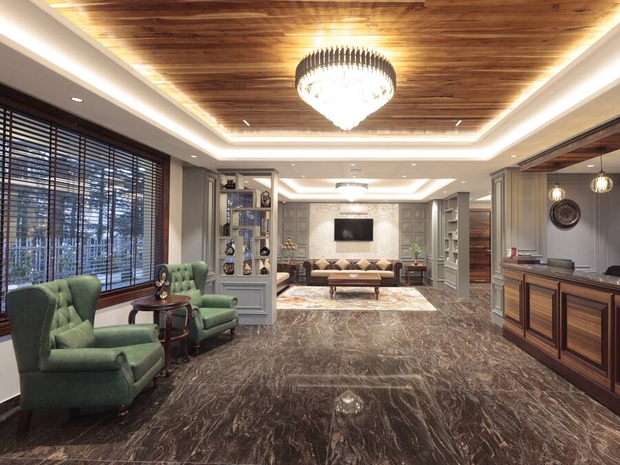 A spacious lobby with a wooden ceiling, a chandelier, a sofa, and a reception desk.