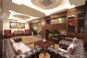 A spacious lobby with leather sofas, a wooden coffee table, and a painting on the wall.