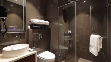 A modern bathroom with a large sink, toilet, and glass-enclosed shower.