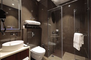 A modern bathroom with a large sink, toilet, and glass-enclosed shower.